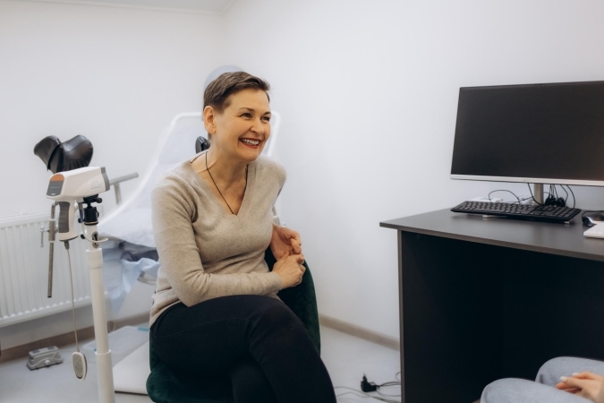 Older woman with short hair smiling during a gynecology appointment.